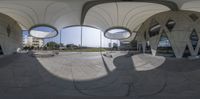 a distorted fisheye photo of circular buildings in an office complex with modern architecture on it