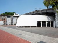 a building with a giant white dome next to a walkway and brick sidewalk next to it