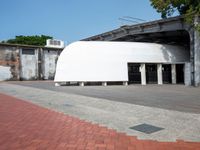 a building with a giant white dome next to a walkway and brick sidewalk next to it