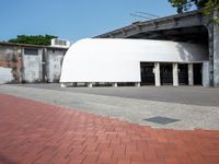 a building with a giant white dome next to a walkway and brick sidewalk next to it