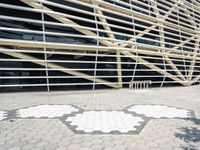 a building that has several geometric shapes on the ground in front of it with a tree and sidewalk