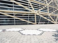 a building that has several geometric shapes on the ground in front of it with a tree and sidewalk