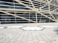 a building that has several geometric shapes on the ground in front of it with a tree and sidewalk