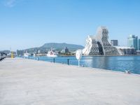 a man sitting on his bike near a waterway with water in the background, and some buildings by the shore