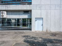 a concrete building with a parking lot in front of it on the sidewalk next to a bicycle rack and sidewalk