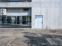 a concrete building with a parking lot in front of it on the sidewalk next to a bicycle rack and sidewalk