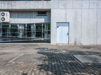 a concrete building with a parking lot in front of it on the sidewalk next to a bicycle rack and sidewalk