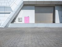 a red stop sign in front of a building with some pink shutter doors in front of it