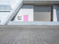 a red stop sign in front of a building with some pink shutter doors in front of it