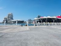 a concrete path leading up to water with boats in the background at a city boat dock