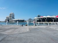 a concrete path leading up to water with boats in the background at a city boat dock