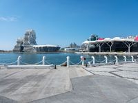 a concrete path leading up to water with boats in the background at a city boat dock