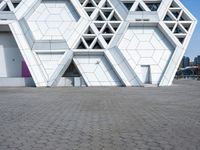 a white building with several smaller blocks next to each other on a brick road in front of it