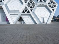 a white building with several smaller blocks next to each other on a brick road in front of it