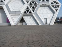 a white building with several smaller blocks next to each other on a brick road in front of it