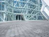 a stone paved sidewalk and an outdoor courtyard with a tall building with a glass facade