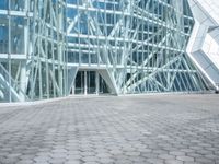 a stone paved sidewalk and an outdoor courtyard with a tall building with a glass facade