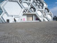 a large white building with geometric design on it's side and a person in yellow shorts walking past