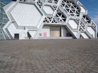 a large white building with geometric design on it's side and a person in yellow shorts walking past