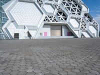 a large white building with geometric design on it's side and a person in yellow shorts walking past