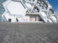 a large white building with geometric design on it's side and a person in yellow shorts walking past