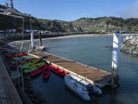 some kayaks and some white boats by the water and rocks and mountains in the background