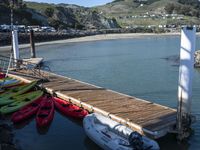 some kayaks and some white boats by the water and rocks and mountains in the background