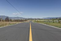 a empty road with a line in it and mountains in the background in autumn colors