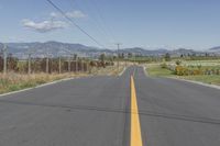 a empty road with a line in it and mountains in the background in autumn colors