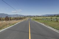 a empty road with a line in it and mountains in the background in autumn colors