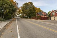 a street in an neighborhood that appears to have leaf fallen on the side of the road