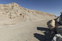 there is a bike rider on a paved dirt road through rocky area near a mountain