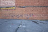 an asphalt parking lot with the word fire hydrant in color written on it and a brick wall in the background