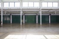 empty commercial warehouse with large windows and concrete floors with multiple colors of doors and green walls