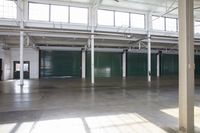 empty commercial warehouse with large windows and concrete floors with multiple colors of doors and green walls