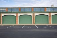 the four garages in this building have green doors and one door opened to see a parking area