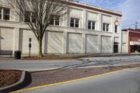 a large white building with a clock sitting next to it on the side of a road