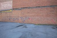 graffiti is on a brick wall and street corner near fire hydrant in an empty parking lot