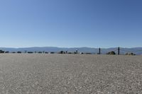 an asphalt field with many umbrellas on it and mountains in the background in the distance