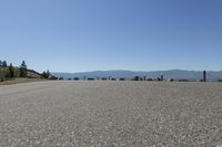 an asphalt field with many umbrellas on it and mountains in the background in the distance