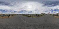 an empty road going to the far side of it with a cloudy sky and some small clouds