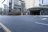 an empty street near an office building with glass walls and white stripes on the sidewalk