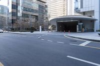 an empty street near an office building with glass walls and white stripes on the sidewalk