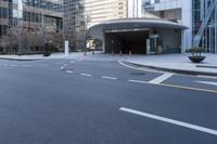 an empty street near an office building with glass walls and white stripes on the sidewalk