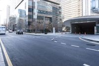 an empty street near an office building with glass walls and white stripes on the sidewalk