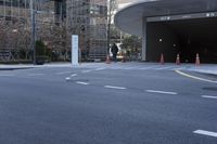 an empty street near an office building with glass walls and white stripes on the sidewalk