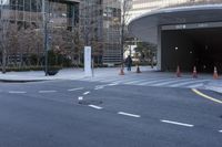 an empty street near an office building with glass walls and white stripes on the sidewalk