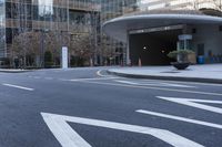 an empty street near an office building with glass walls and white stripes on the sidewalk