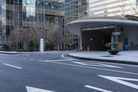 an empty street near an office building with glass walls and white stripes on the sidewalk