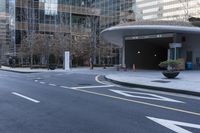 an empty street near an office building with glass walls and white stripes on the sidewalk